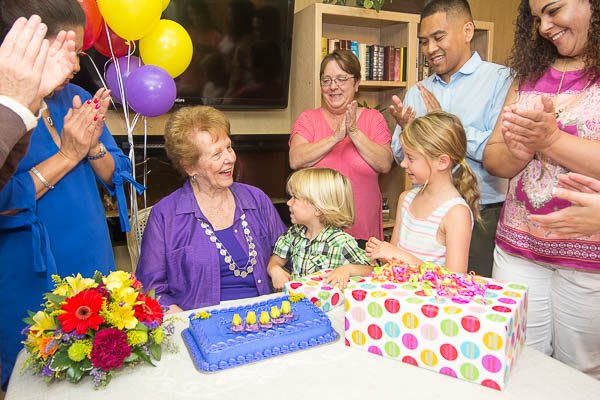 A joyful family gathering celebrating a birthday with cake and balloons.