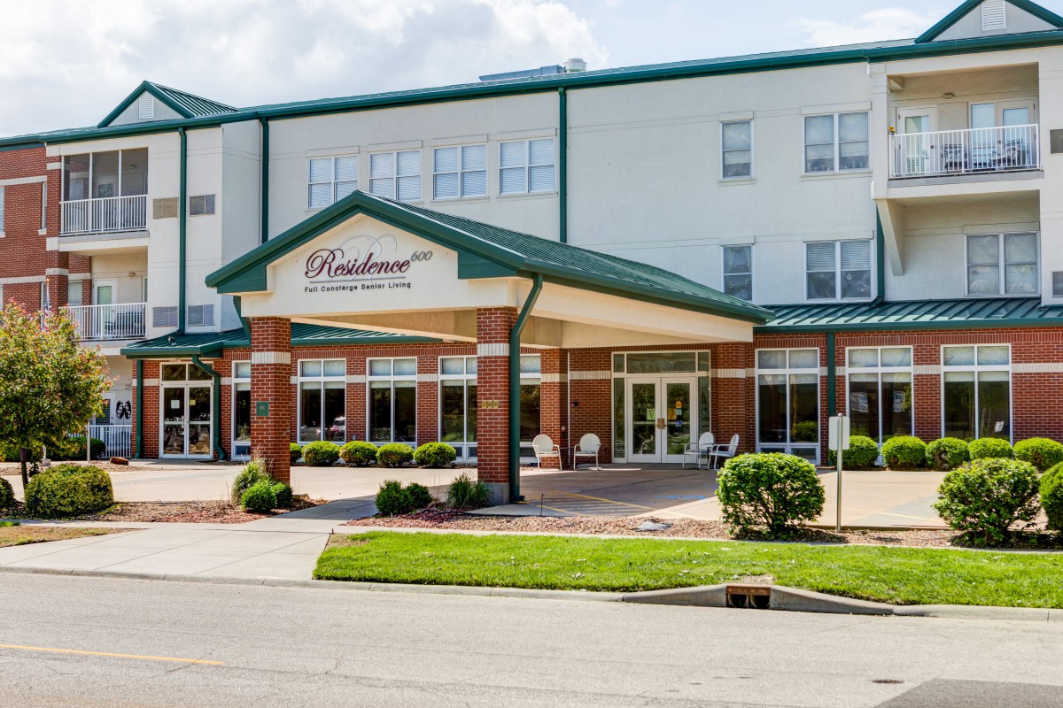 The entrance of a hotel with a landscaped exterior.