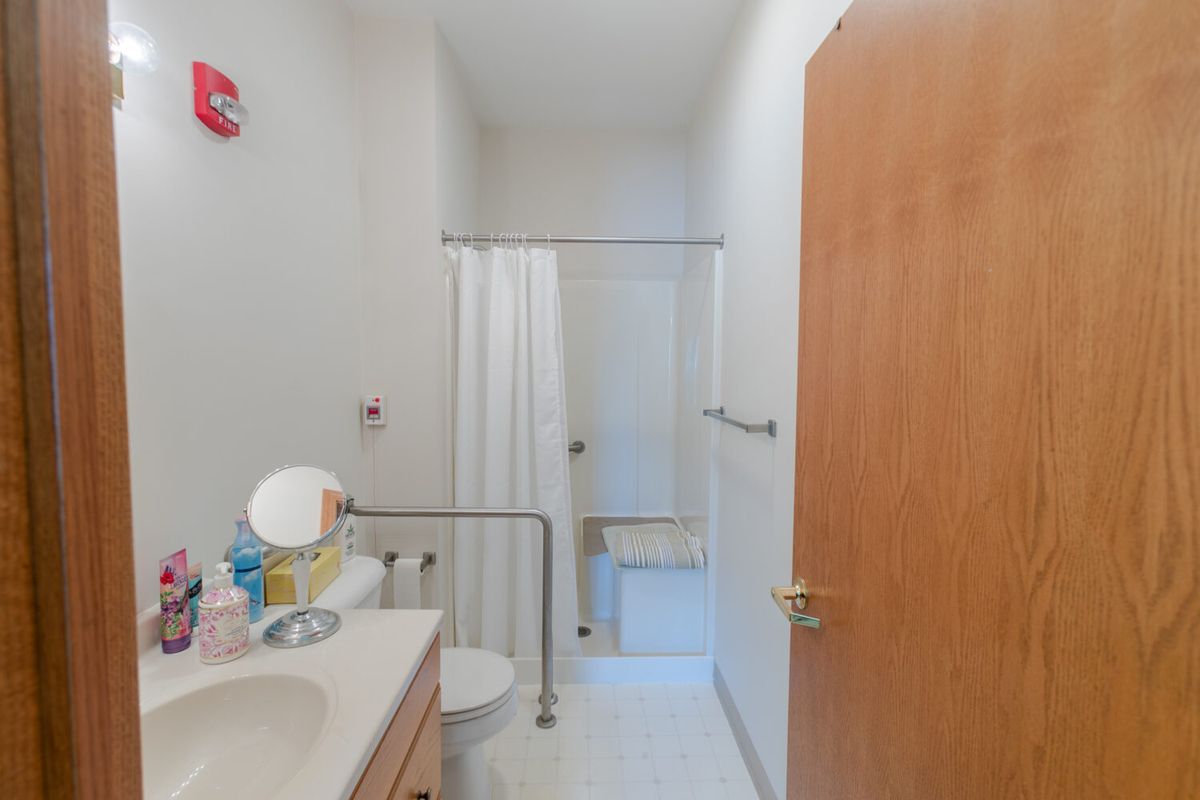 A small bathroom interior with a sink, mirror, shower, and toilet.