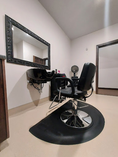 A stylist's workspace featuring a barber chair and large mirror, designed for beauty and grooming services.
