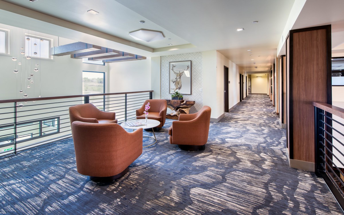 A modern lobby with a seating area featuring comfortable chairs and a patterned carpet.