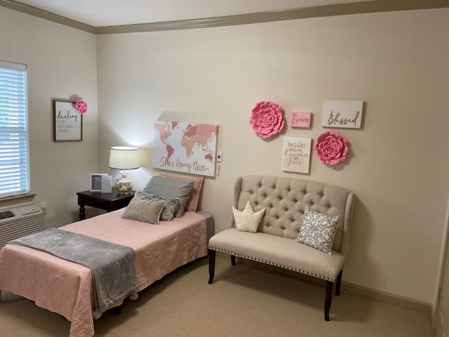 A cozy bedroom with pink accents and elegant wall art.