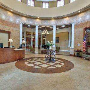 A spacious and elegantly designed lobby with a reception desk, columns, and stylish decor.