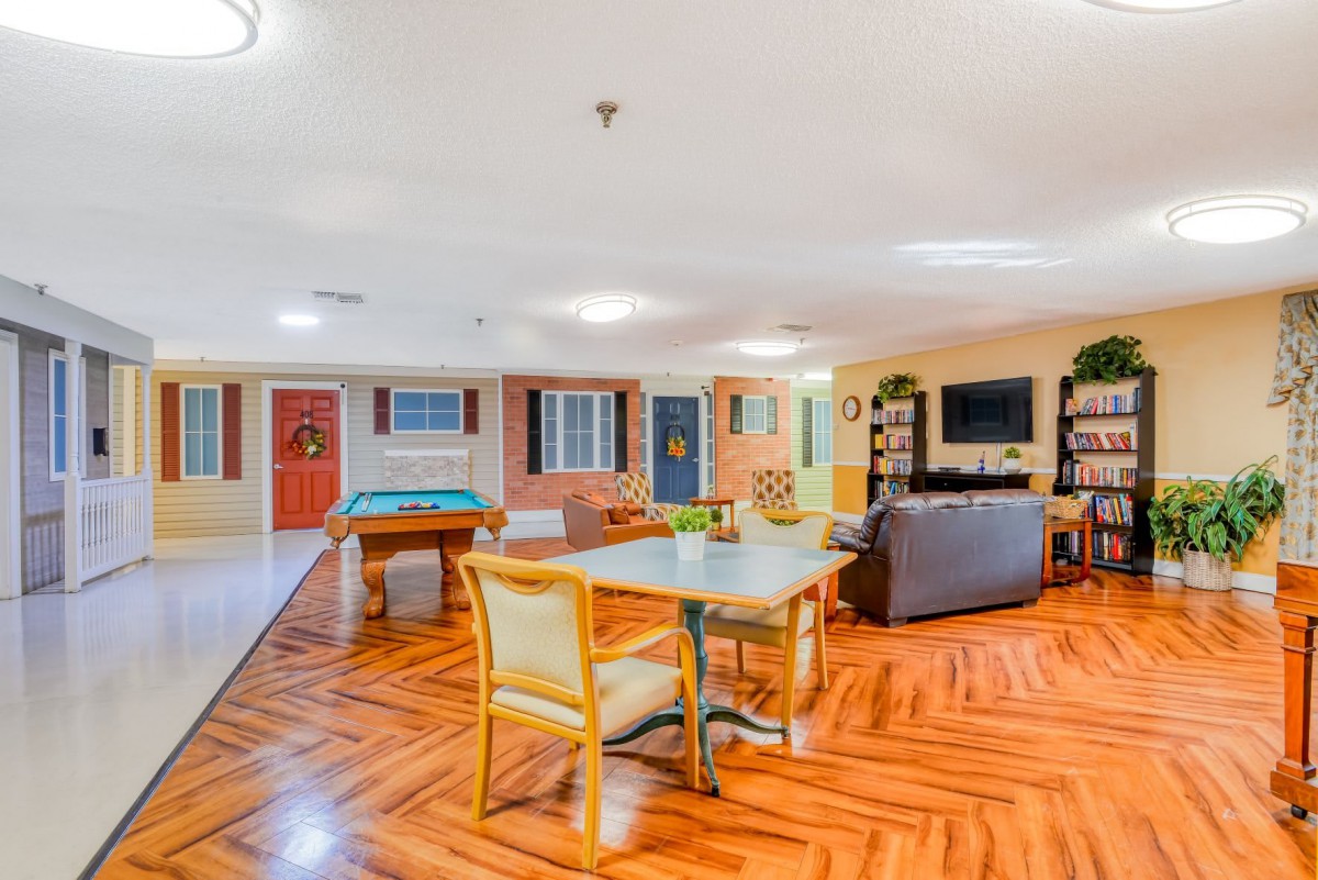 A spacious living room with vibrant colors, featuring a cozy seating area, entertainment setup, and a table with chairs.