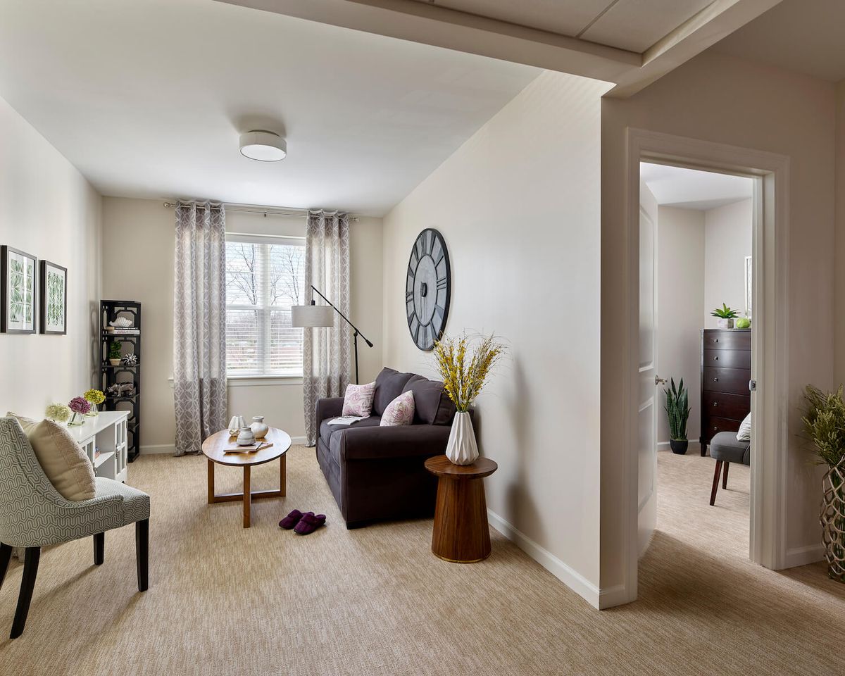 A cozy living room with a sofa, coffee table, and large window with curtains.