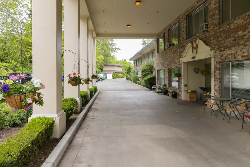 A view of a hotel entrance with a covered driveway and landscaped surroundings.
