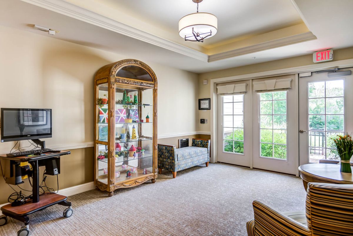 A cozy living room with a display cabinet and large windows.