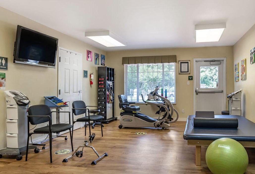 A physical therapy room equipped with exercise machines and seating.