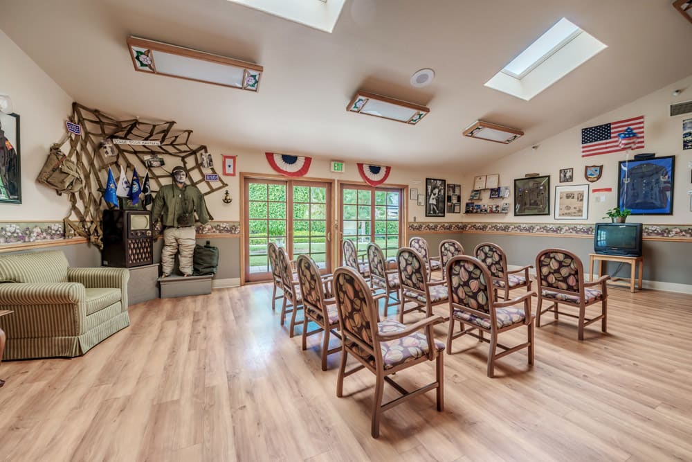A small museum exhibit room with rows of chairs, decorated with flags and uniforms on display.