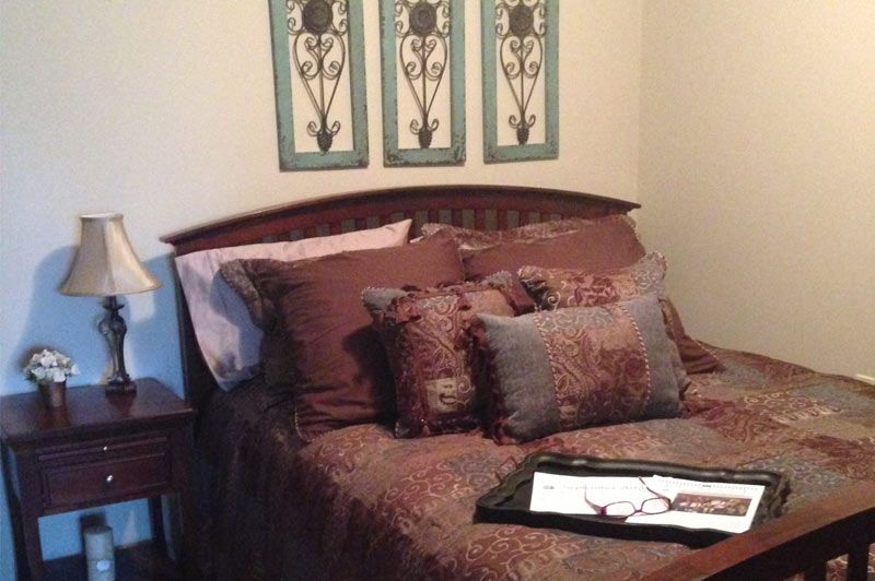 A cozy bedroom with decorative pillows and artwork.