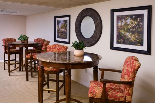 A cozy seating area with a round table, chairs, and decorative art on the walls.