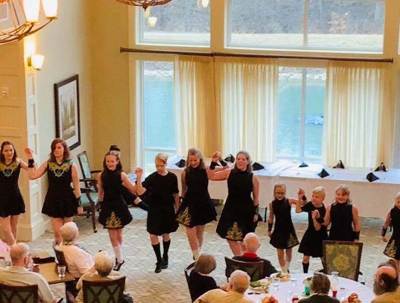 A group of dancers performing in front of an audience at an indoor event.