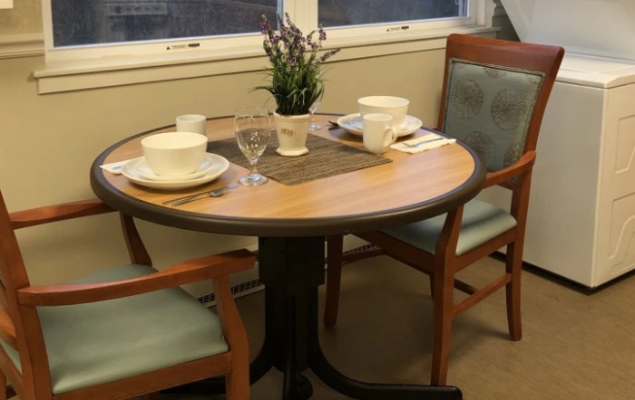 A small dining table set with cups and plates, adorned with a plant centerpiece.