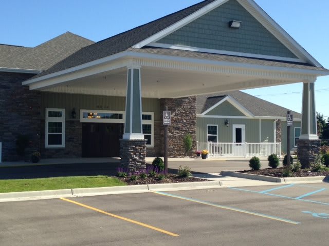 A modern building with a covered entrance and a parking lot.