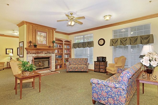 A cozy living room with a fireplace, surrounded by bookshelves and comfortable seating.