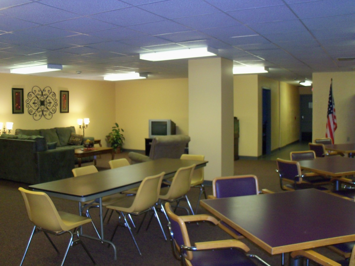 A cozy common area with tables, chairs, and a television.