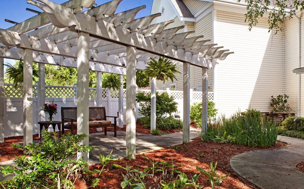 A tranquil garden pergola with wooden benches and lush greenery.