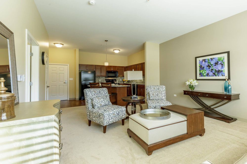 A modern open-concept living room connected to the kitchen, featuring stylish furniture and neutral tones.