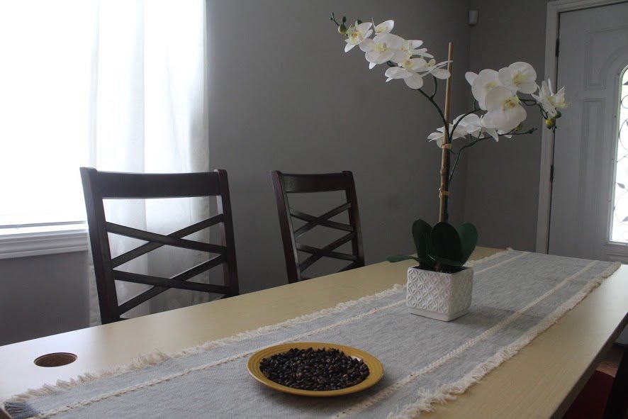 A dining table with a decorative orchid and a plate of berries.