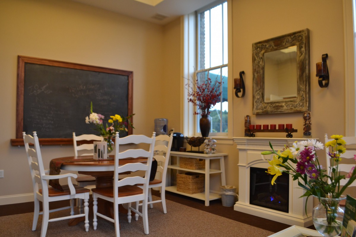 A cozy dining room with a round table, chairs, and a decorative fireplace.