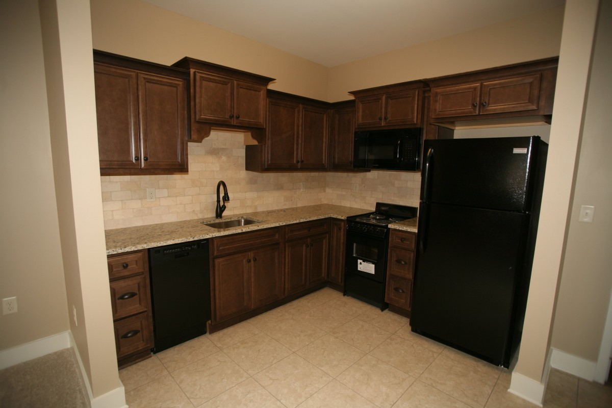 Modern kitchen with dark wooden cabinets and black appliances.