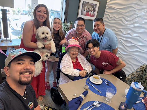 A joyful family gathering with smiles, love, and a furry friend at the table.