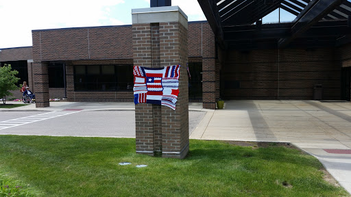 A decorative display featuring multiple flags on a pillar outside a building.