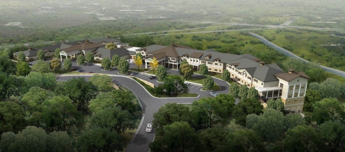An aerial view of a complex surrounded by greenery and winding roads.