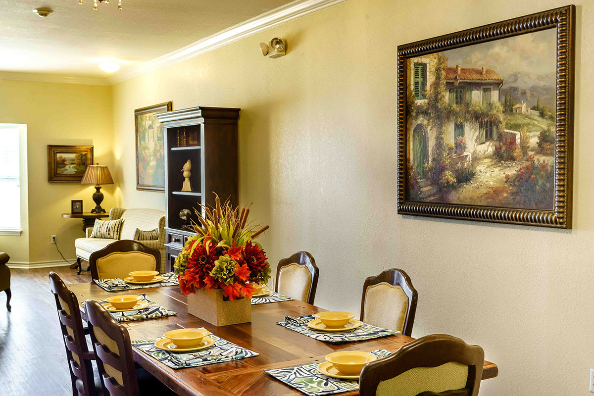 A well-decorated dining room with a wooden table, chairs, and vibrant floral centerpiece.