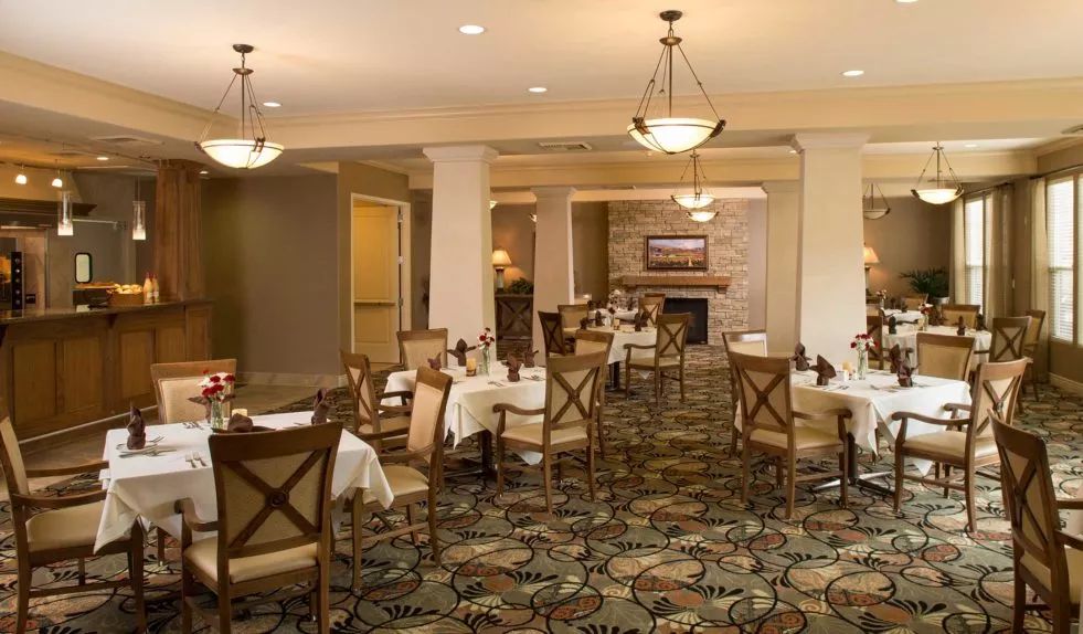 An elegant dining room with neatly arranged tables and chairs, warm lighting, and a cozy atmosphere.