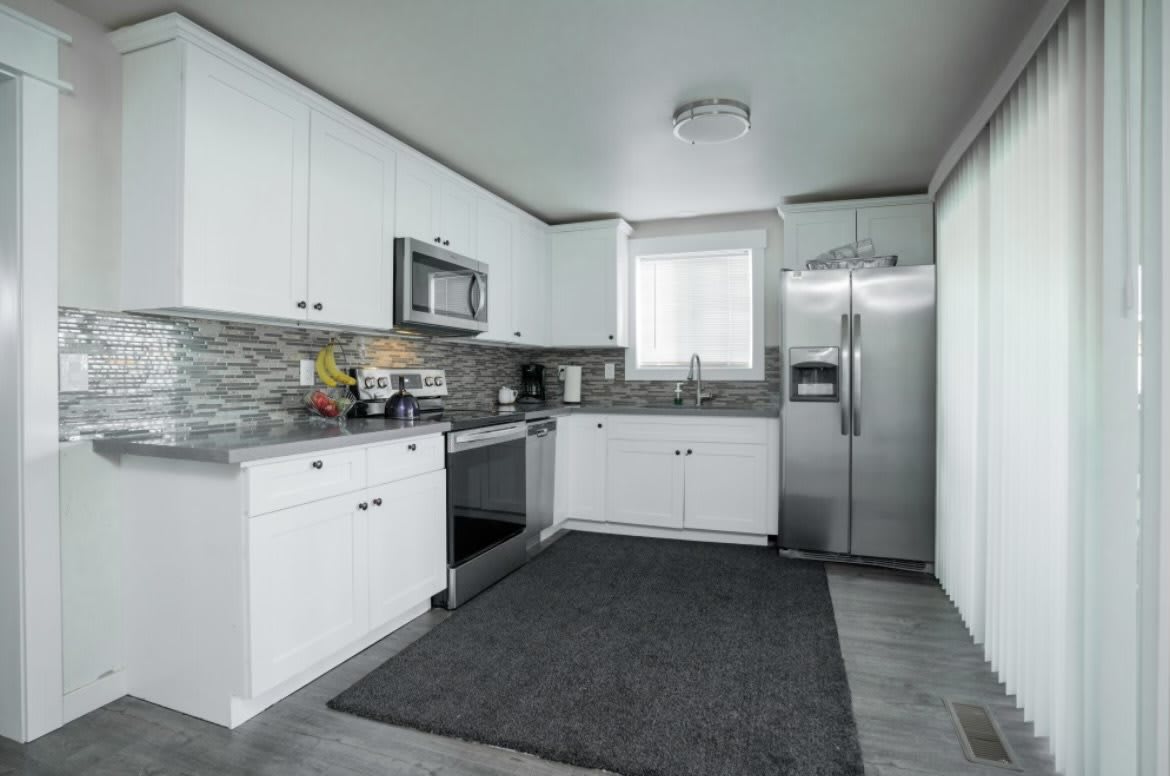 A modern kitchen with white cabinetry and stainless steel appliances.
