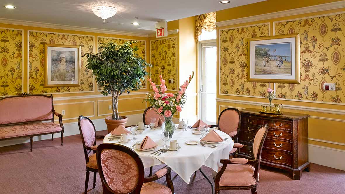 An elegantly set dining table with a floral centerpiece in a tastefully decorated room.