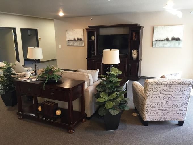 A cozy living room setup featuring a sofa, armchair, wooden furniture, and indoor plants.