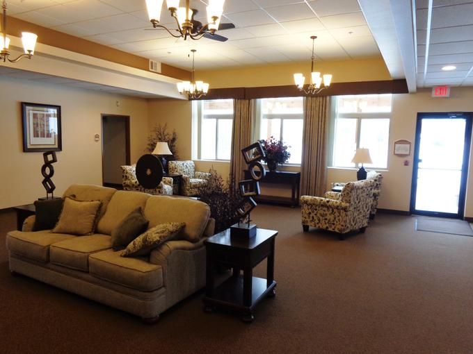 A cozy living room with sofas, armchairs, and large windows providing natural light.