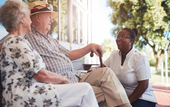 An elderly man enjoying a conversation with a caregiver outdoors.