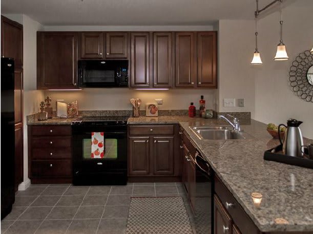 A modern kitchen with dark wood cabinets and granite countertops.