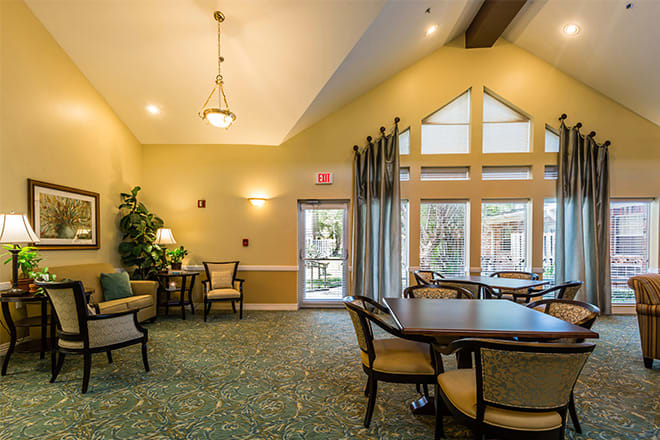 A cozy living room with comfortable seating, a table, and large windows allowing natural light.