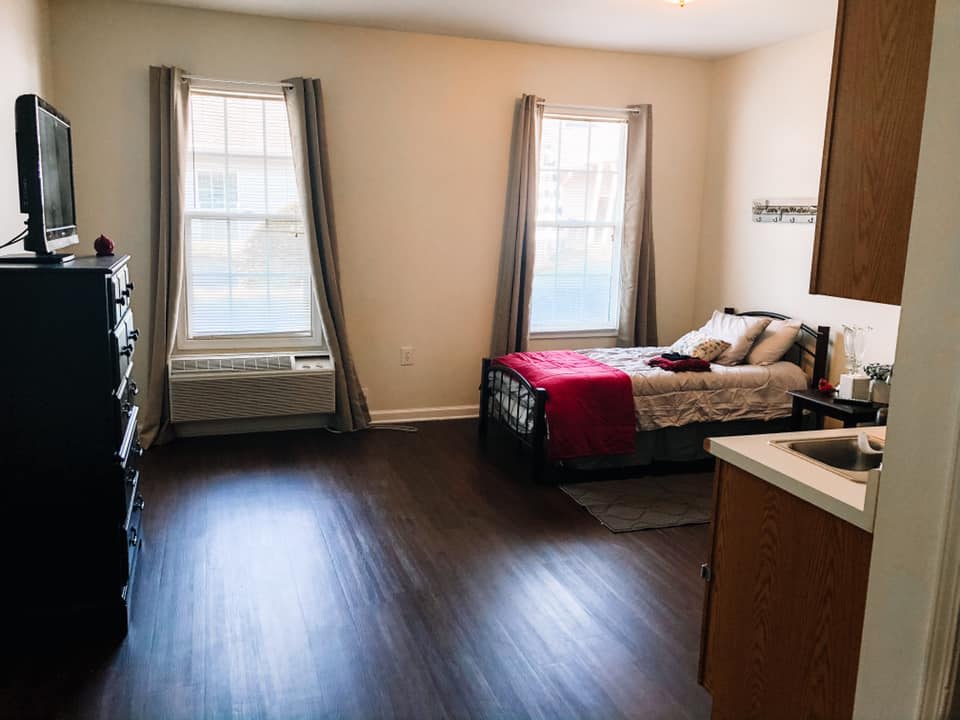 A modern and minimalist bedroom with ample natural light and wood flooring.