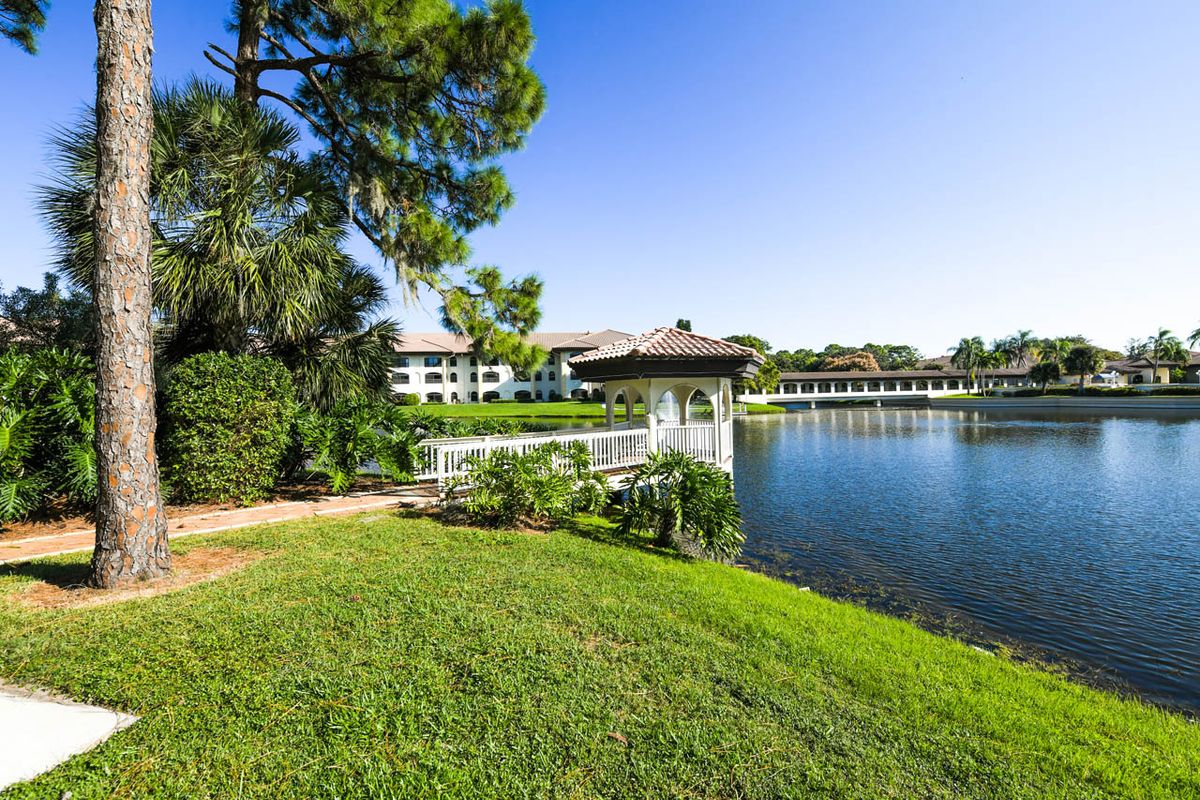 A scenic view of a resort by the lake with a bridge connecting green spaces.