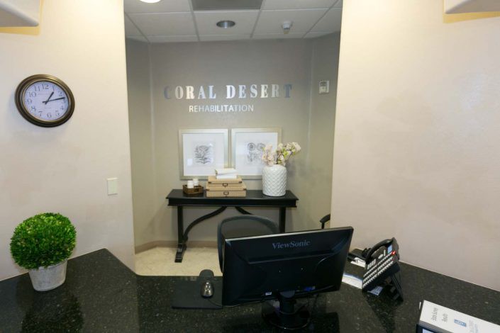 A reception area in a dental office with a desk, computer, and decorative elements.