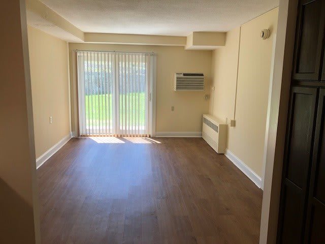 An empty room with hardwood floors and a sliding glass door letting in natural light.
