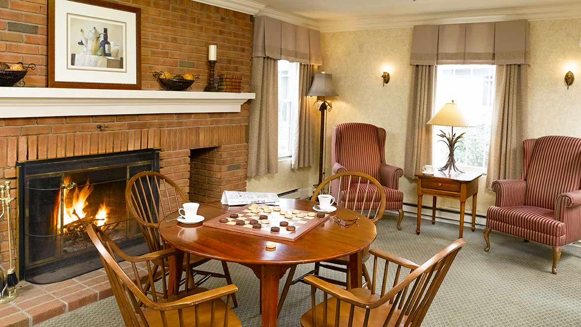 A cozy living room with a wooden table and chairs near a brick fireplace.