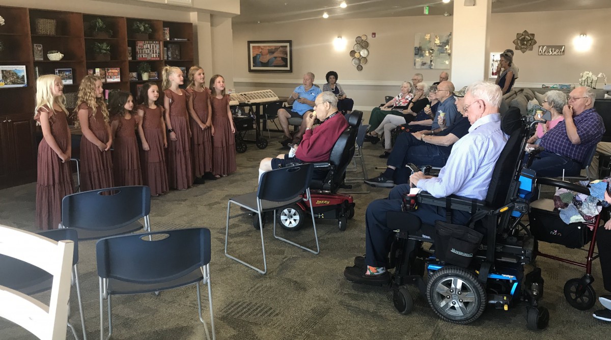 A group of young choir singers is performing for an elderly audience in a nursing home.