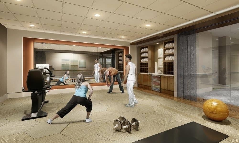 People exercising in a modern gym with mirrors and weights.