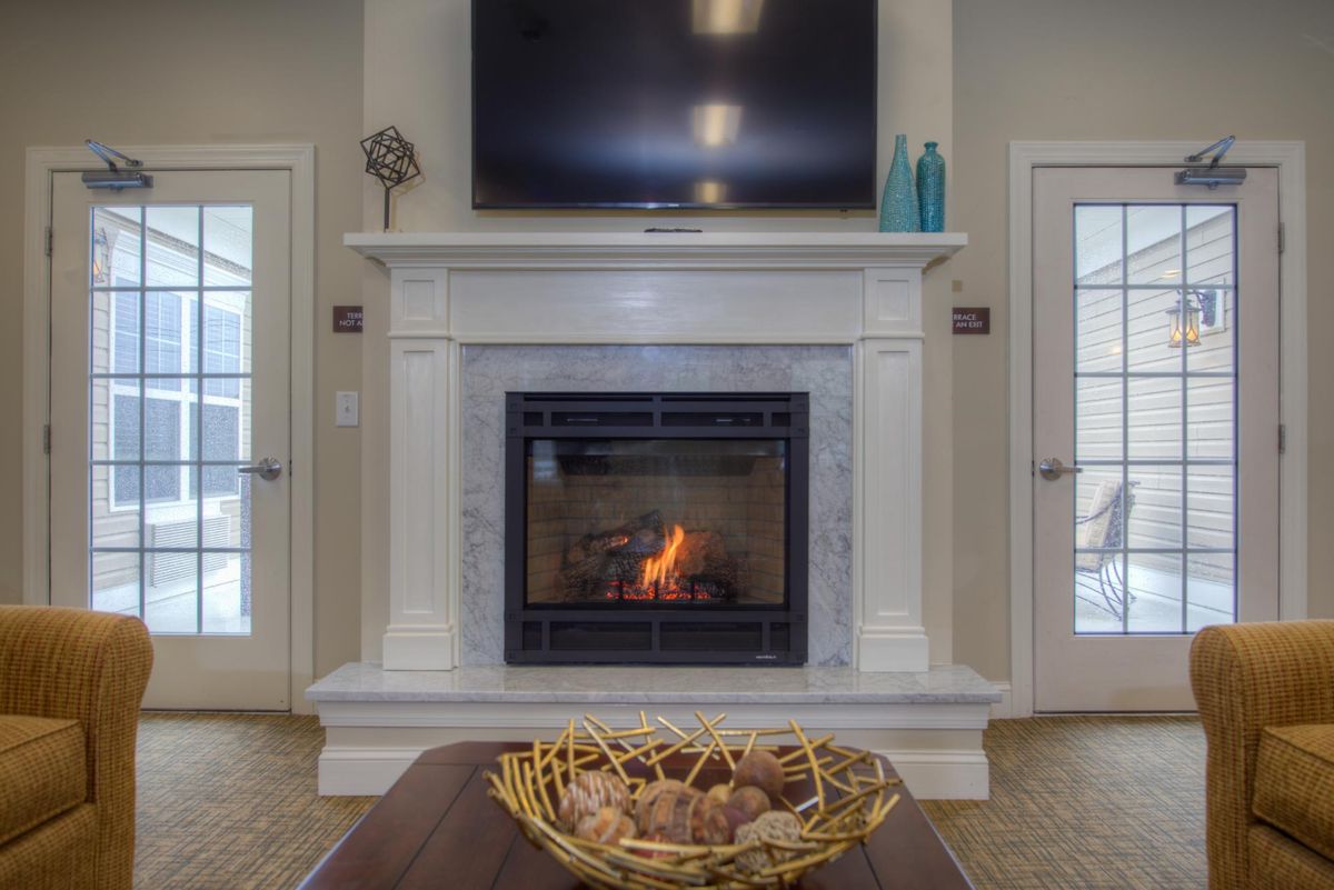 A cozy living room with a modern fireplace and a TV mounted above it.