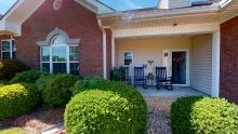 A cozy front porch with rocking chairs and neatly trimmed hedges.