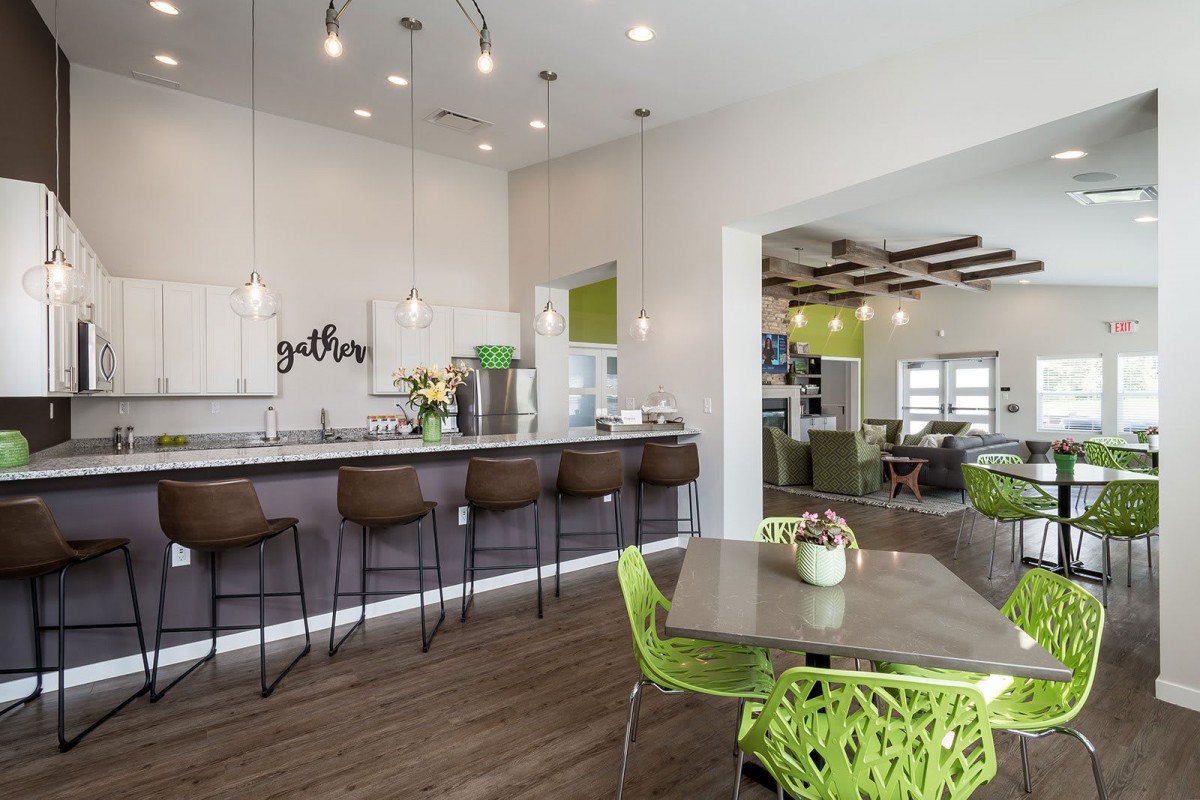 A contemporary kitchen with bar seating and green accent chairs.