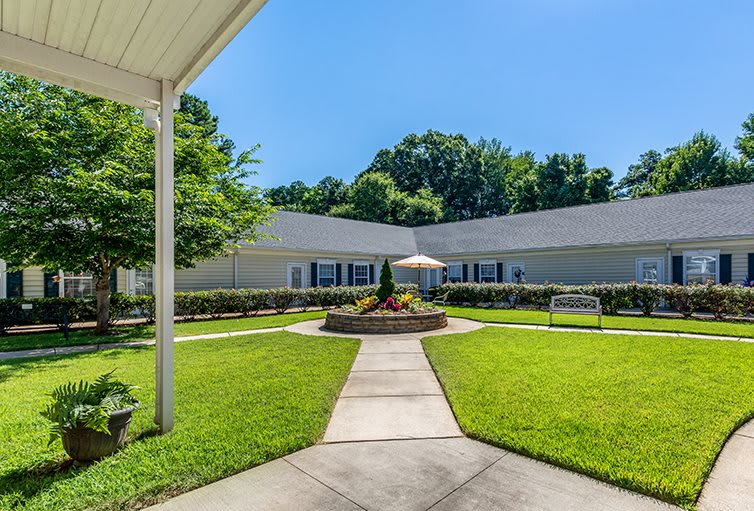 A well-maintained building with a landscaped lawn and walkway under a clear blue sky.