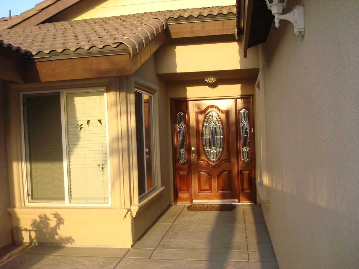 A residential house entrance with a wooden front door and adjacent windows.