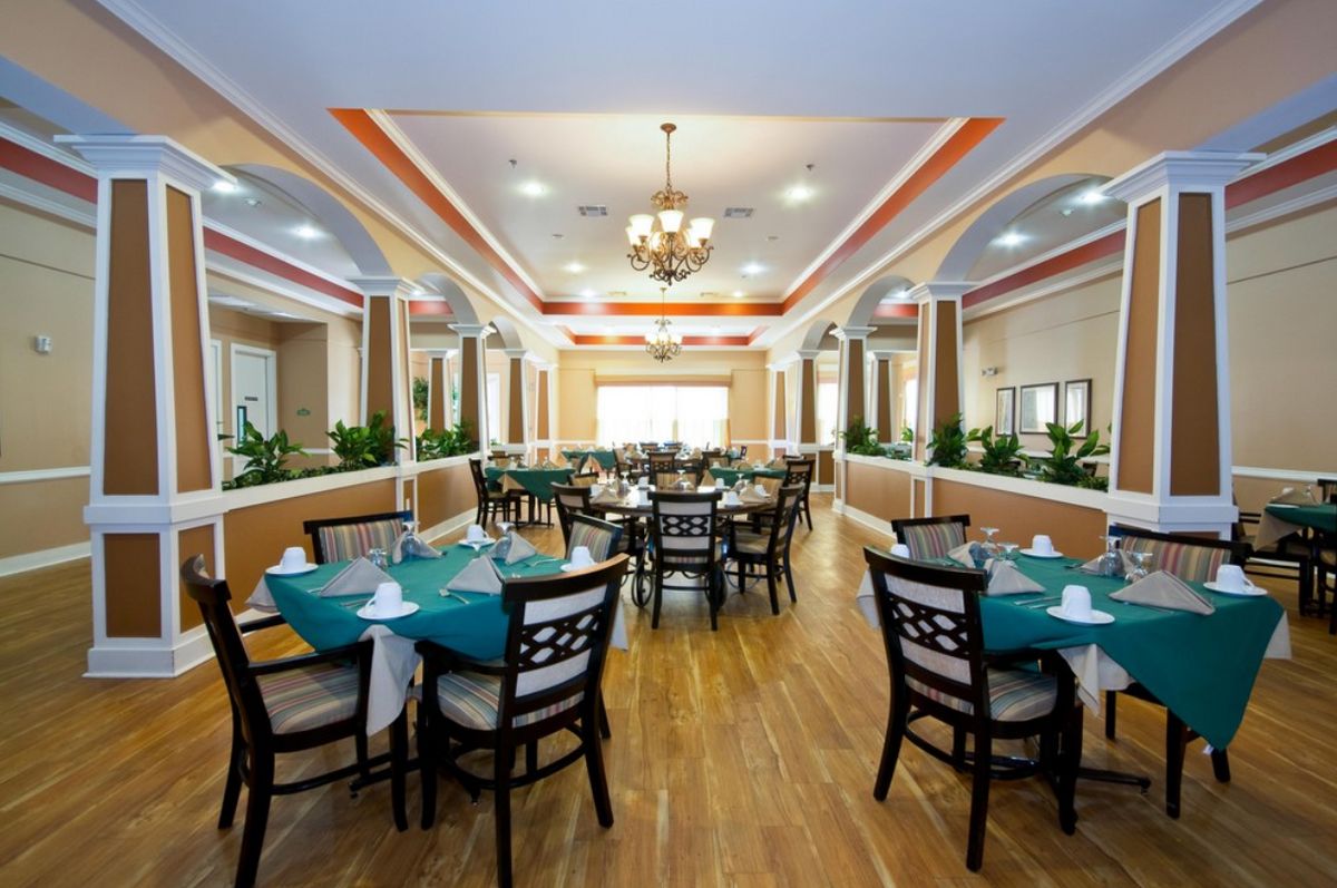 A spacious and elegant dining area with neatly arranged tables and chairs, adorned with chandeliers.